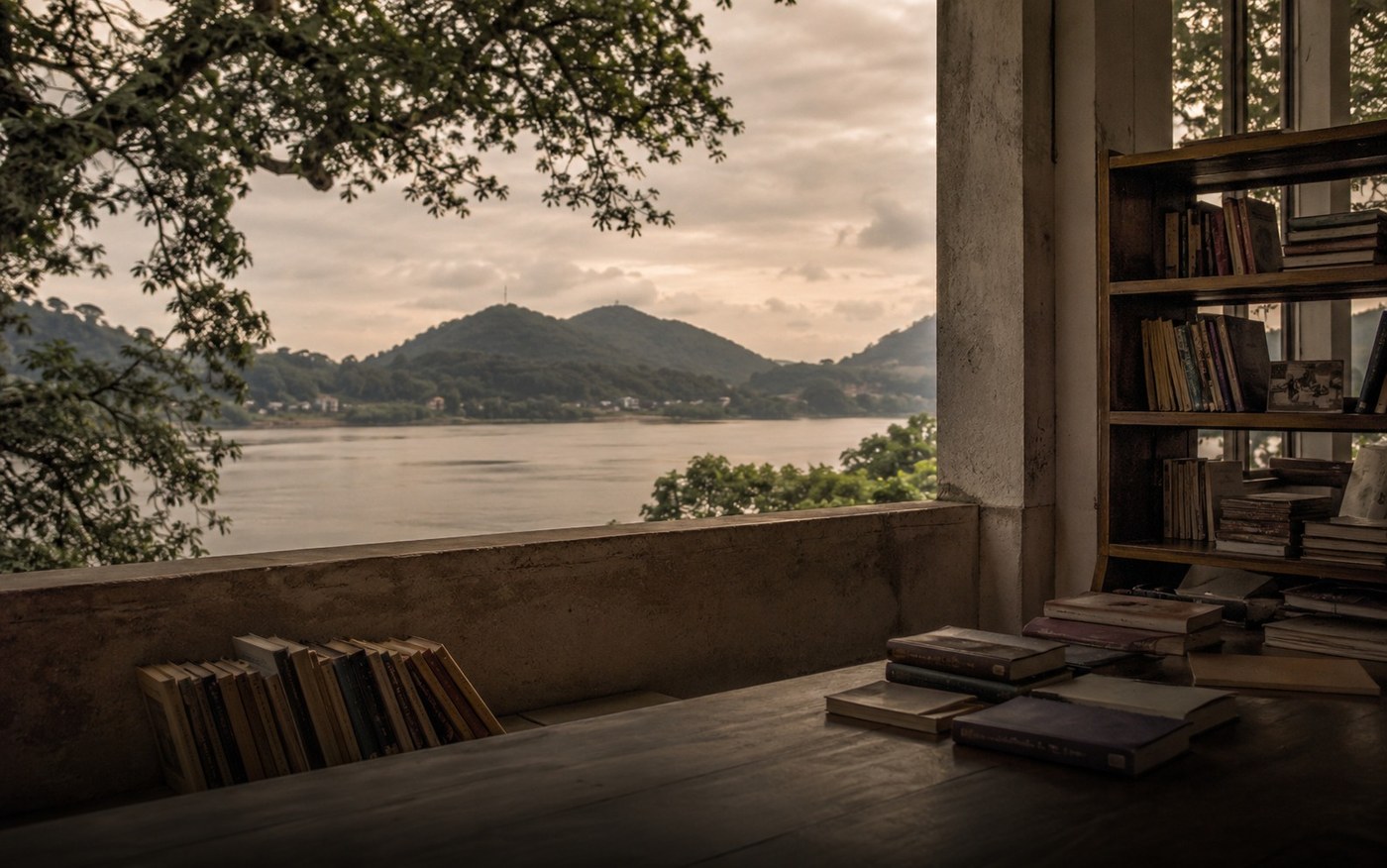 Guwahati quiet reading space with books and a river landscape beyond